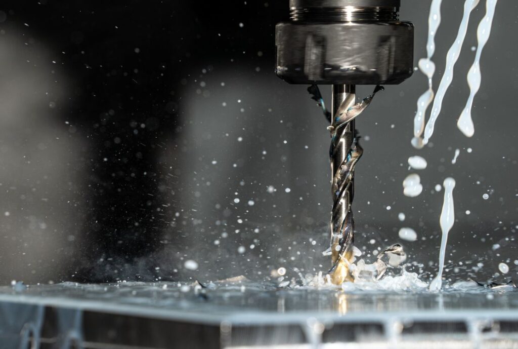 Close-up of a CNC cutting head with coolant spray