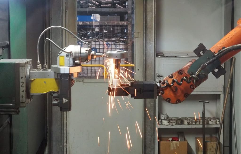 Automated industrial cutting cell throwing sparks inside a metal fabrication shop